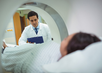 Patient in MRI scanner while healthcare professional looks on